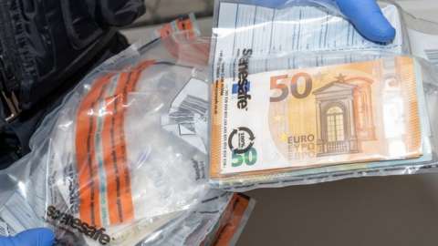 A police officer holding money that has been placed in a bag