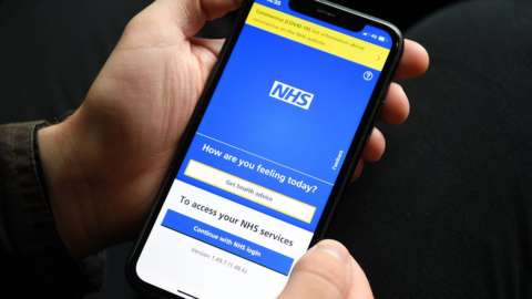 Hands seen holding a smartphone that is displaying the NHS Covid app