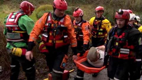 Rescuers carry a man to safety in flood water