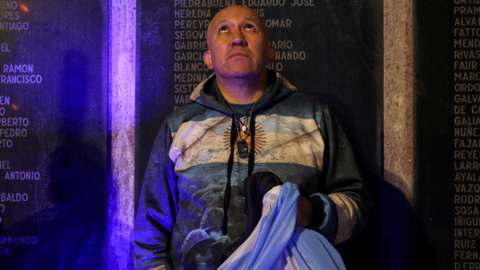 An Argentinian holds his country's flag in front of a memorial dedicated to those who died in the 1982 war