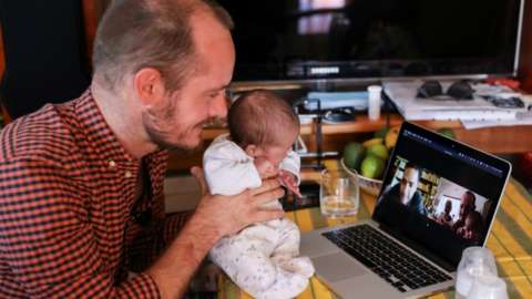 Namibian citizen Phillip Luhl holds one of his twin daughters as he speaks to his Mexican husband Guillermo Delgado via Zoom meeting in Johannesburg,