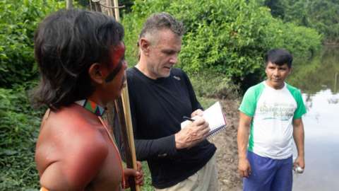 Veteran foreign correspondent Dom Phillips (C) talks to two indigenous men in Aldeia Maloca Papiú, Roraima State, Brazil, on November 16, 2019.