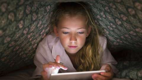 Stock shot of child under covers with tablet computer