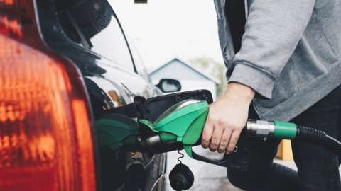 Person filling a fuel tank at petrol station