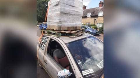 Car with heavy load of bricks on roof