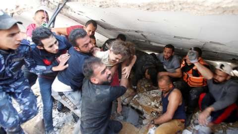 Rescuers carry Suzy Eshkuntana, 6, as they pull her from the rubble of a building at the site of Israeli air strikes, in Gaza City (16 May 2021)