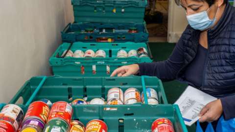 A volunteer packs and prepares food parcels at the Tottenham food bank at Tottenham Town Hall on 21 January 2021 in London, England.