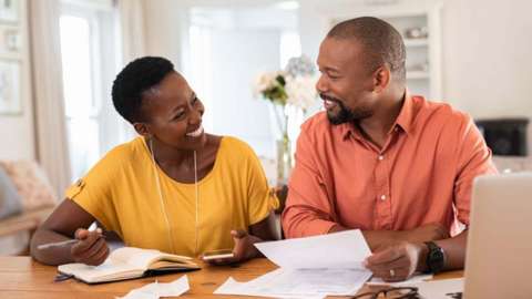 A woman and man deal with paperwork while sat at a table
