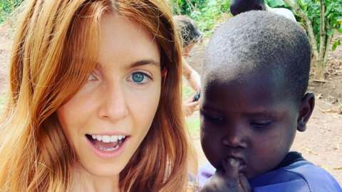 Stacey Dooley in Uganda, posing with a young child