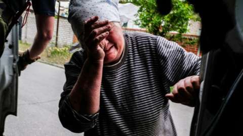 Woman crying in Severodonetsk as her daughter leaves on a van 25 May 2022