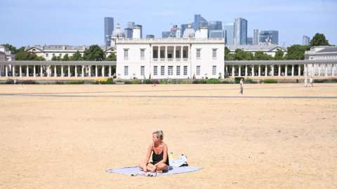 A woman sunbathes on parched ground in Greenwich Park in London