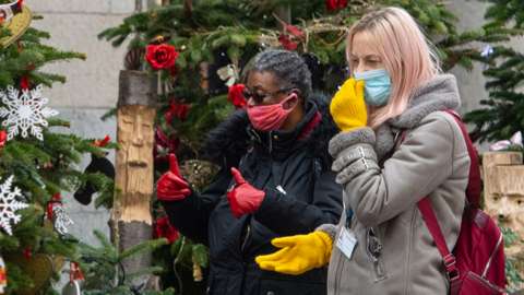 Women in face masks looking at Christmas trees
