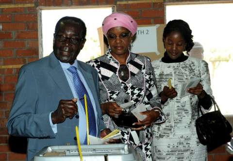 Zimbabwe President Robert Mugabe (L) casts his vote by his wife Grace and daughter Bona (R) at a polling booth in a school in Harare on July 31, 2013.