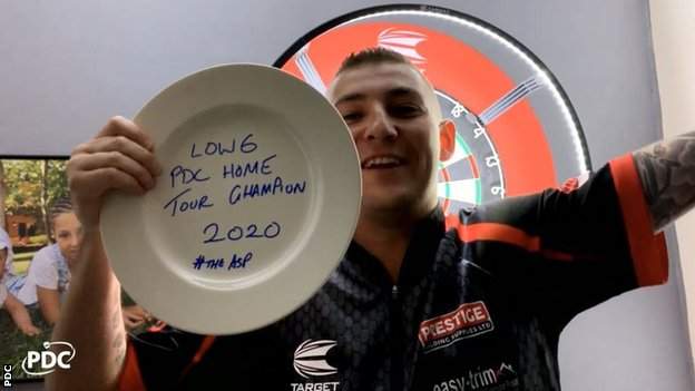 Nathan Aspinall holds up a trophy made out of a dinner plate to celebrate winning the PDC Home Tour title