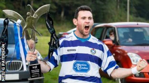 A Newtonmore player celebrates with the Premiership trophy