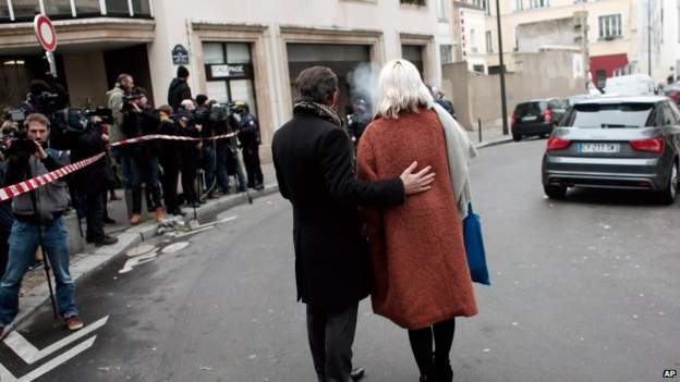 People stand outside the French satirical newspaper Charlie Hebdo