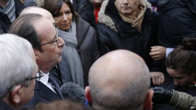 French President Francois Hollande (2nd on the left) talks to the press upon his arrival at the headquarters of the French satirical newspaper Charlie Hebdo