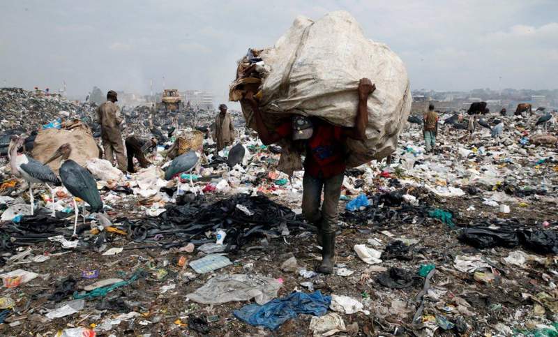 A man collects plastic bags from a dumping site