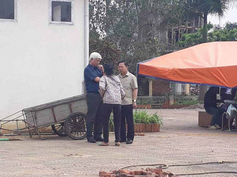 Đại biểu Quốc hội Dương Trung Quốc và Lưu Bình Nhưỡng nói chuyện với người dân trong lúc chờ bàn giao người bị giữ.