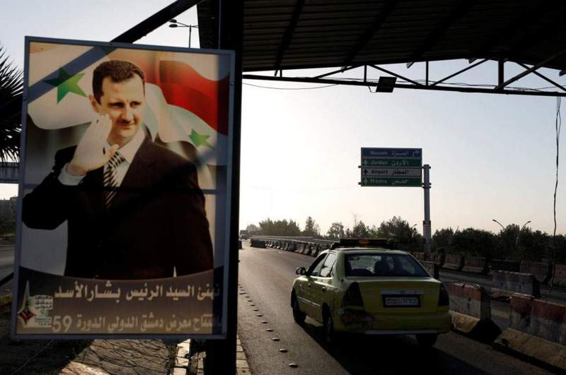 Tấm áp phích lớn in hình Tổng thống Syria Bashar al-Assad trên một con đường đến sân bay