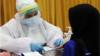 Медицинский работник проверяет женщину на коронавирус в Индонезии