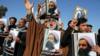 Протестующие иракские шииты выкрикивают лозунги против правительства Саудовской Аравии, держа плакаты с изображением шейха Нимра аль-Нимра
