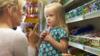 Ребенок берет шоколад с полки супермаркета