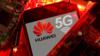 Логотипы Huawei и 5G видны среди груды светящихся красных печатных плат (PCB)