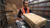 Рабочий Amazon загружает пакет в грузовик
