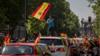 На изображении показан мужчина, размахивающий испанским флагом, когда он принимает участие в автомобильной акции протеста