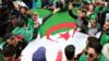 Люди несут национальный флаг Алжира в Алжире. Файл фото
