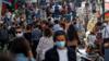 Люди в масках идут по оживленной улице Парижа