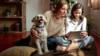 Мать, дочь и собака перед планшетным компьютером
