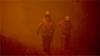 Пожарные тушат лесной пожар в густом дыму в городе Моруя, к югу от залива Батманс, в Новом Южном Уэльсе, 4 января 2020 года.