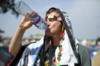 Посетитель фестиваля пьет воду в жару в Гластонбери
