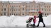 Женщина толкает детскую коляску по горам снега в Москве