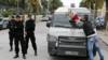 Полицейский в штатском (справа) возлагает цветы, полученные от гражданского, на полицейскую машину на месте взрыва бомбы в автобусе, в котором ехали охранники президента Туниса