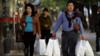 Китайская пара с сумками для покупок выходит из торгового центра в Пекине