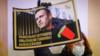 Протестующий держит плакат с хэштегами «Навальный был отравлен», «Мы знаем, кто виноват» и «Алексей, останься в живых»