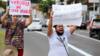 Два протестующих несут таблички «Стыдно за то, что они белые» и «Пожалуйста, прекратите убивать нас» возле супермаркета Carrefour в Порту-Алегри, Бразилия, 20 ноября 2020 года