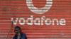 Мужчина сидит у опущенных ставен магазина, на ставнях которого нарисован логотип Vodafone в Мумбаи, Индия, 24 февраля 2019 г.