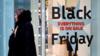 Покупатели передают рекламный знак скидок «Черная пятница» возле магазина на Оксфорд-стрит в Лондоне 26 ноября 2019 г.