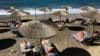 Туристы наслаждаются солнцем на пляже в Эрмонесе на Корфу, Греция