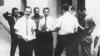 Ли Харви Освальд (впереди слева) стоит рядом с человеком, которого Комиссия Уоррена не опознала, в центре в белой рубашке, раздает листовки для Комитета Честной игры Кубы