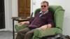 Роджер Рис-Эванс дома в своем кресле, окруженном технологиями