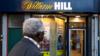 Мужчина смотрит на букмекерскую контору William Hill