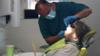 Стоматолог обслуживает пациента в клинике Silveroaks Dental Surgery, поскольку в Милтон-Кинсе открываются возможности для проведения обследований без образования аэрозолей