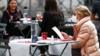 Женщина читает меню, сидя на террасе ресторана в Риме, 25 октября 2020 г.