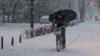 мужчина едет на велосипеде под сильным снегопадом в центре города Любляна, Словения (13 января 2017 г.)