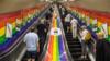 Люди катаются на трубчатом эскалаторе, украшенном цветами флага Pride